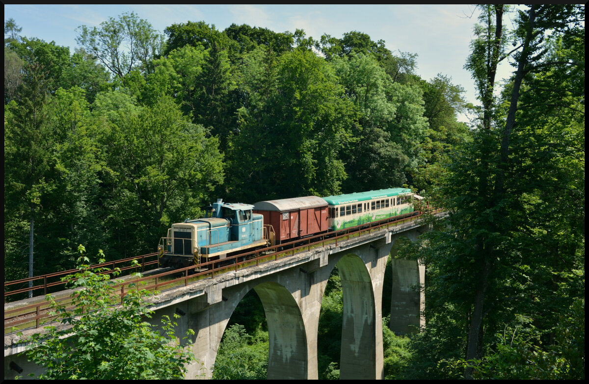 Mit der LEO (Lokalbahn Endorf Obing) ins Grüne: Am 04.06.2023 kommt die V60 (260 106-0, Logistik Wiesböck GmbH Kiefersfelden) mit dem Esslinger Beiwagen (95 80 0303 003-7 D-LOGWI), dem Packwagen (Gkklms 27 80 1385 003-9 D-BKE) sowie am Zugschluss die Köf 323 699-9 über den Viadukt bei Amerang gerollt.