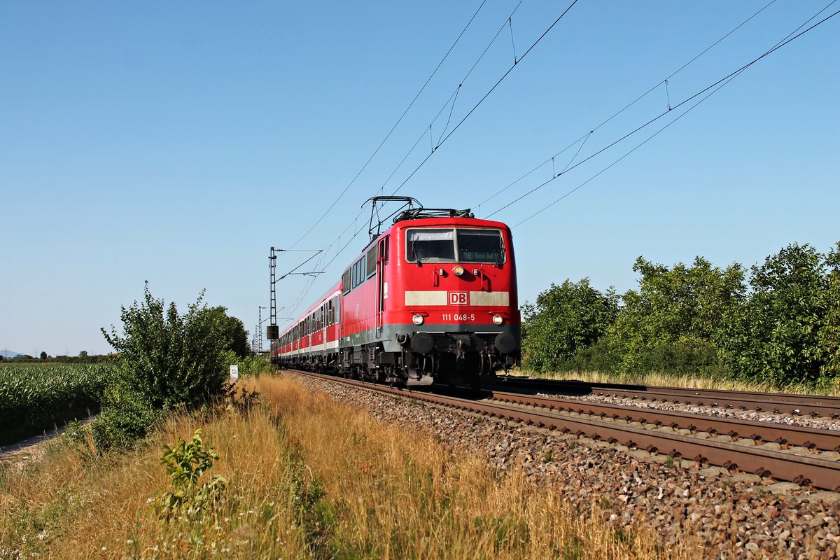 Mit einer RB (Offenburg - Basel Bad Bf) kam am Nachmittag des 10.07.2015 die Freiburger 111 048-5 bei Hügelheim in Richtung nächsten Zwischenhalt in Müllheim (Baden) vorbei.