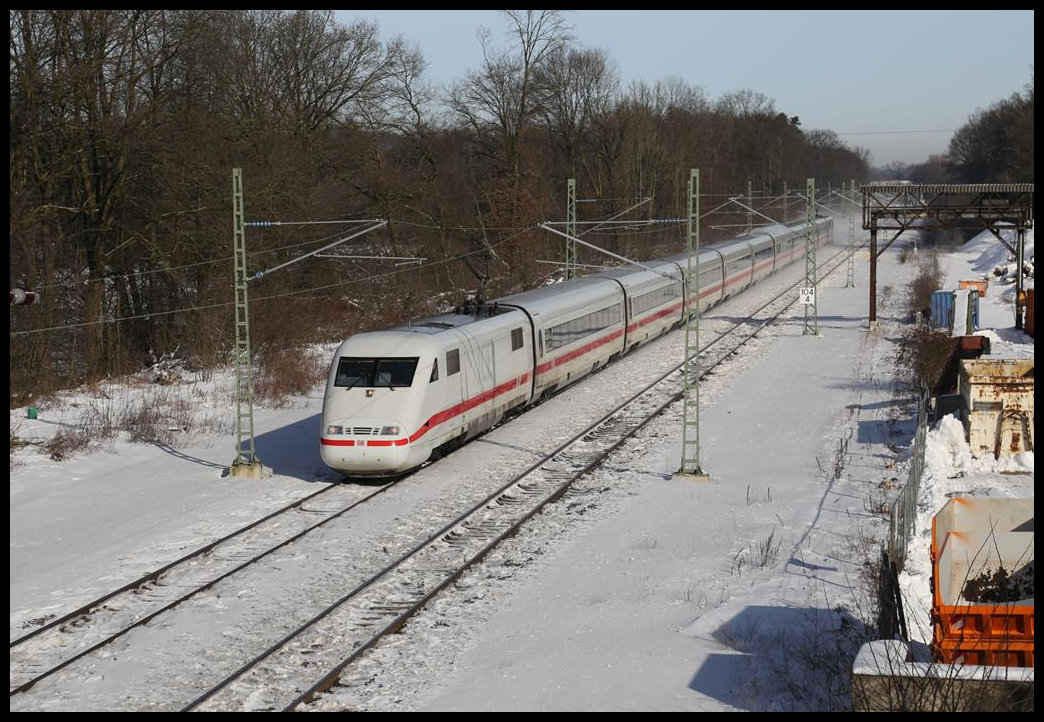 Mit rund zwanzig Minuten Verspätung fährt hier ein ICE 1 nach Köln am 14.02.2021 um 11.43 Uhr durch den bis auf zwei Durchgangsgleise zurück gebauten Bahnhof Natrup Hagen. Der Brücken Kran auf der rechten gehörte einst zum Bahnhofsbereich. Mit ihm wurde ein fünftes Gleis bedient. Heute steht er auf einem Privatgelände.