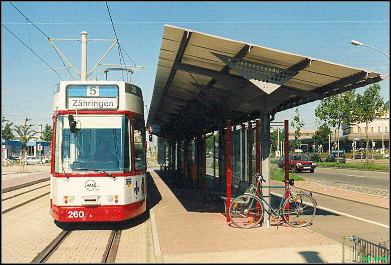 Mit der Straßenbahn nach Freiburg-Haid -

Die Endhaltestelle 'Haid - Munzinger Straße' mit einer großzügigen Überdachung, erschließt den südlichen Teil des ausgedehnten Gewerbegebietes. Innerhalb der Wendeschleife sind die Bushaltestelle angeordnet. In ferner Zukunft wird von hier möglicherwiese eine Straßenbahnstecke durch St. Georgen bis zur Endhaltestelle in Vauban gebaut.

Da die Aufnahme nicht der Mindestgröße entspricht und auch qualitative Mängel aufweist soll sie hier auch als Platzhalter dienen, bis ich mal wieder Freiburg besuchen kann.

Scan vom Farbfoto, 1994. Die Aufnahme dient auch hier als Platzhalter 