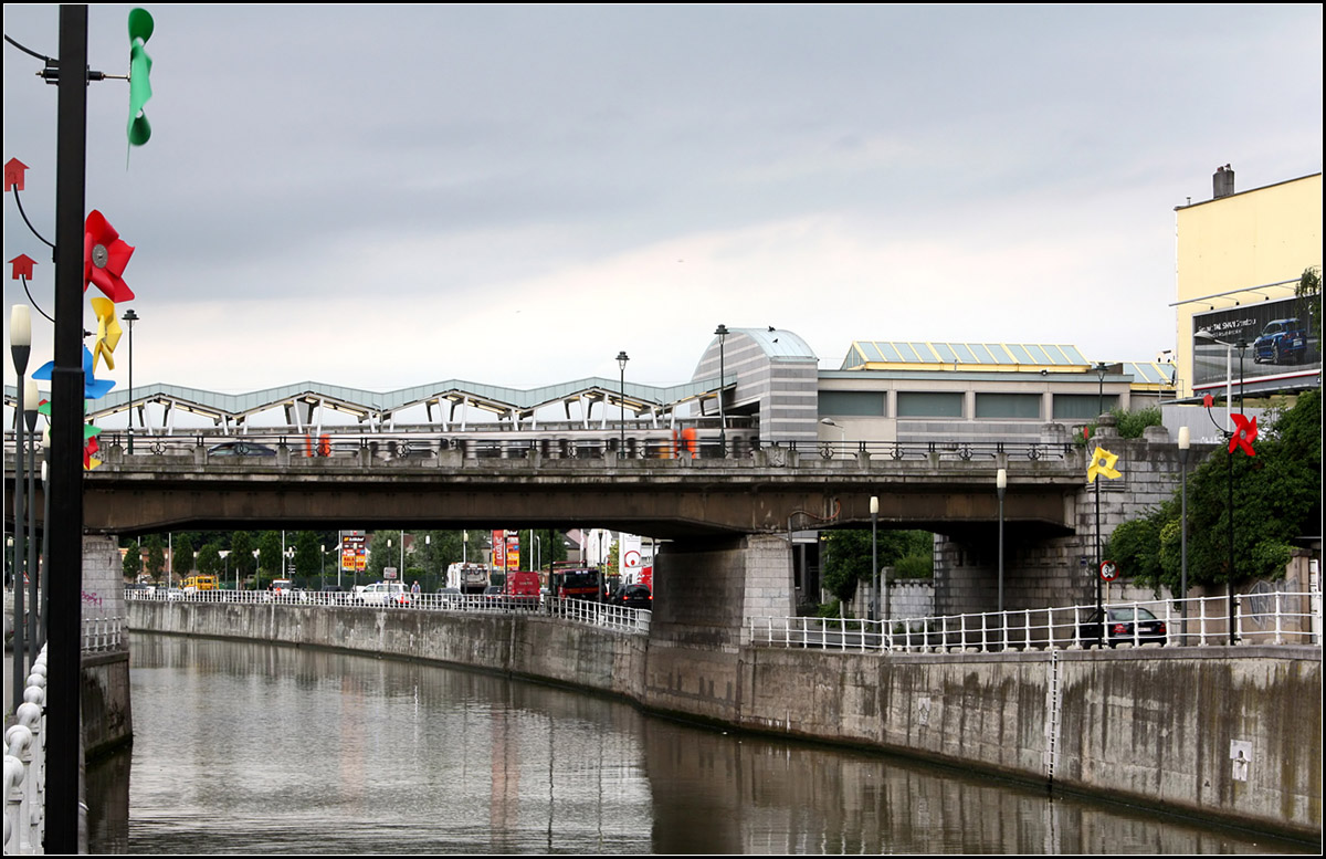 Mit der U-Bahn über den Kanal -

An der Station Delacroix in Kommune Anderlecht verlässt die Brüssler U-Bahnlinie 2 kurz ihre Tunnellage und überquert den Kanal Charleroi-Brüssel auf einer Brücke. Das Stationsbauwerk ist auf der rechten Seite erkennbar. Vom anderen Kanalufer können die Fahrgäste die Station über einen überdachten Zugangsweg auf der Brücke, der zwischen den Gleise liegt, erreichen. Im Bild befindet sich vor der U-Bahnbrücke noch eine Straßenbrücke.

23.06.2016 (M)