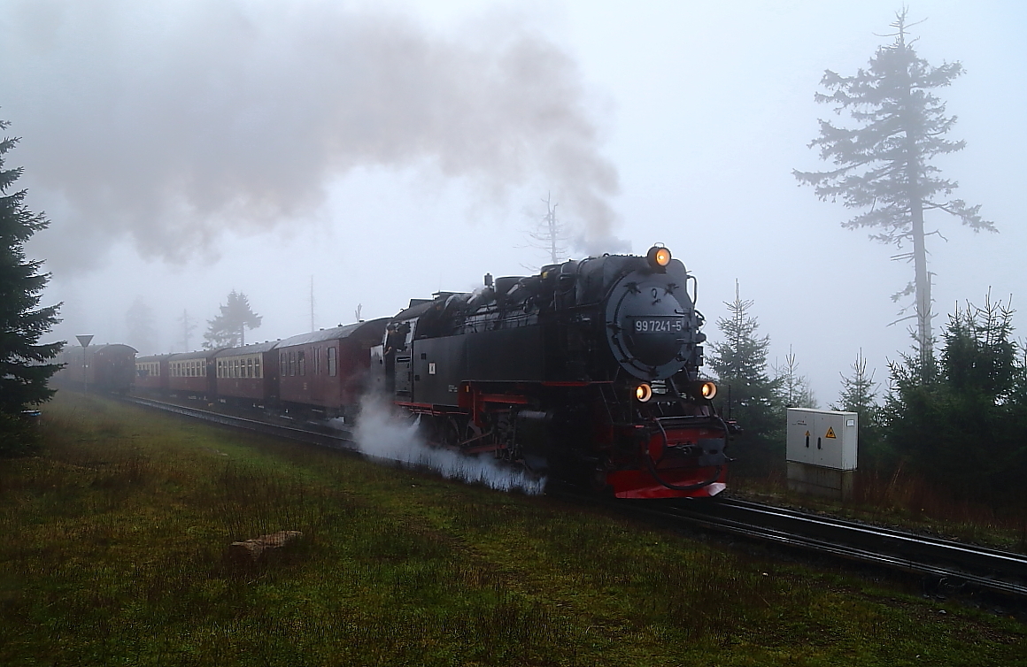 Mit voll ausgelegter Steuerung donnert hier am 17.10.2014 99 7241 mit P8925 über die Weiche an der Ausweichstelle  Goetheweg  bei schönstem Nebel dem Brockenbahnhof entgegen. Links auf dem Stichgleis wartet währenddessen P8932 auf das Freiwerden der Strecke, um seine Talfahrt fortsetzen zu können, sowie davor (nicht im Bild) ein Sonderzug der IG HSB, welcher nach dem Planzug ebenfalls talwärts fahren wird.