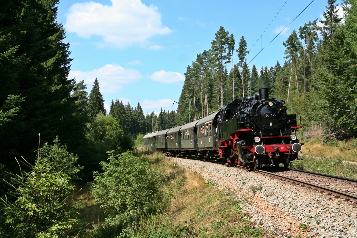  Mit Volldampf durch den Hochschwarzwald... 
...Das war das Motto, unter dem die IG-3Seenbahn e.V. diesen Sommer mit der 86 333 der Wutachtalbahn zwischen Seebrugg und Titisee unterwegs war.
Am 22.08.15 bot sich den Fotografen noch ein kleines Schmankerl, das dem Ein oder Anderen vermutlich nicht direkt aufgefallen ist: Das Zugpersonal verlieh der Lok an diesem Tag kurzer Hand alte, große Reichbahnlampen, mit denen sie früher schon unterwegs gewesen ist.
Nach dem Ende des diesjährigen Einsatzes im Schwarzwald verlies die Lok den Süden Deutschlands und kam erstmals nach über 20 Jahren zurück in ihre alte Heimat nach Sachen, wo sie von nun an von der PRESS zusammen mit der IG 58 3047 Glauchau e.V. vor Sonderzügen eingesetzt werden soll.
Das Bild entstand am besagten 22. August mit dem DPN 87634 von Titisee nach Seebrugg am Einfahrdeckungssignal 3 des Bahnhofs Aha, wo dann die Kreuzung mit der talwärts fahrenden Regionalbahn abgewartet wurde.