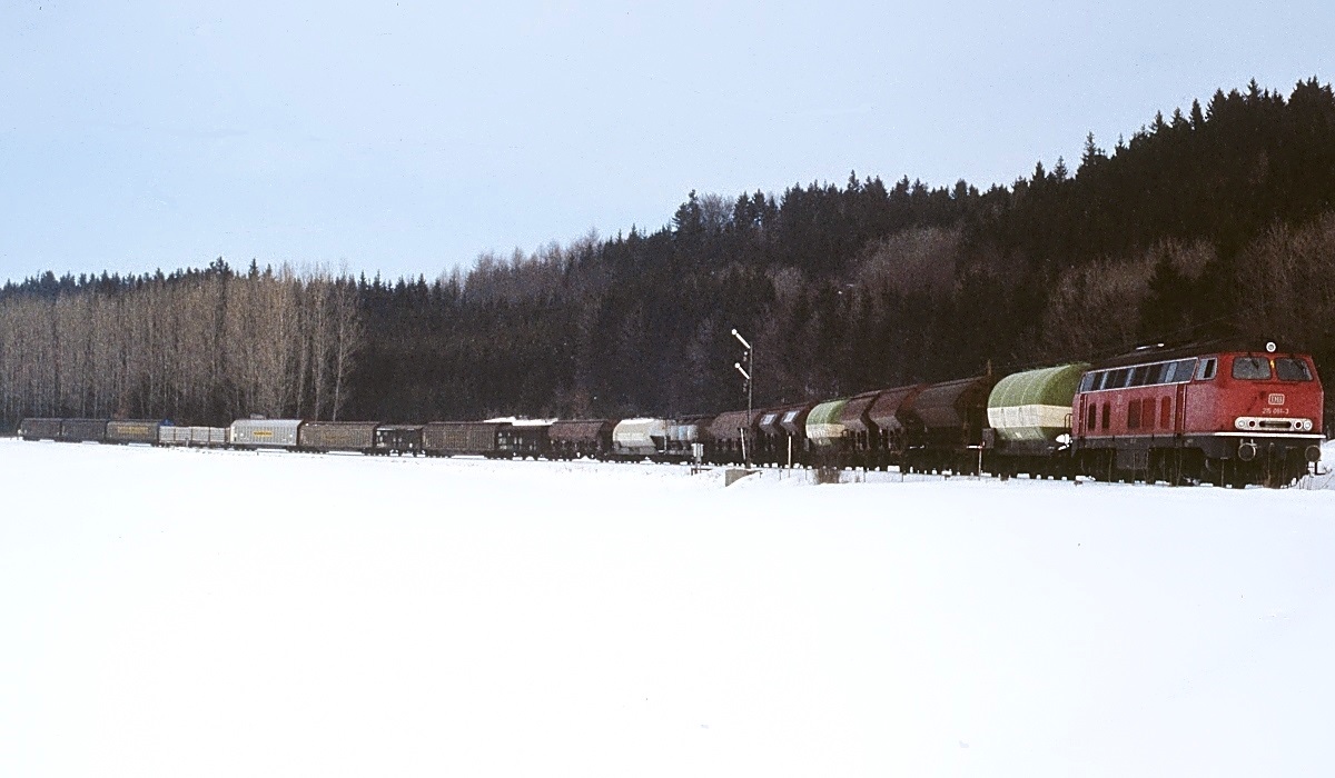 Mit - wenn ich richtig gezählt habe - 20 Güterwagen kommt 215 061-3 am 14.02.1983 die Roßberger Rampe hinunter. Vielleicht eine Anregung für Epoche IV-Modellbahner. Auf der Wiese befindet sich heute ein Solarkraftwerk.