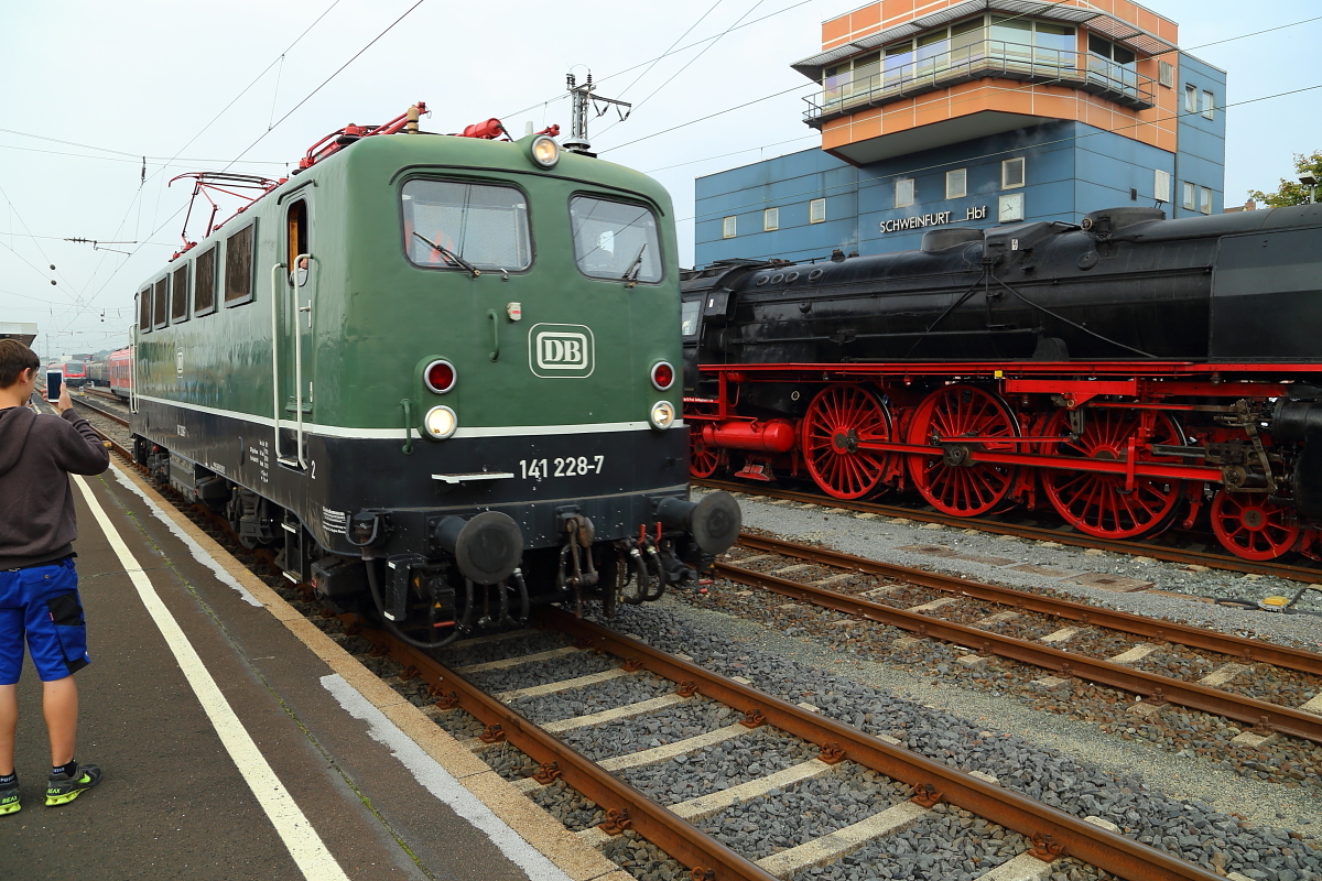 Mit wütendem Pfeifen nähert sich hier am Vormittag des 06.09.2014 E-Lok 141 228 auf Gleis 4 im Schweinfurter Hauptbahnhof. Sie befindet sich gerade auf Rangierfahrt zur Abstellung, nachdem sie nebenstehender Dampflok 01 118 Schubunterstützung bei einer Sonderzugfahrt der Historischen Eisenbahn Frankfurt bis hierher geleistet hat. Das Pfeifen diente der Warnung eines sich für besonders clever haltenden  Superschlauen , welcher hinter mir zum Fotografieren mitten auf den Gleisen stand!!!
Diese Aktion zog dann auch, völlig zu Recht, ein sehr verärgertes Statement der Reiseleitung nach sich. Aber manche begreifen es wohl nie!