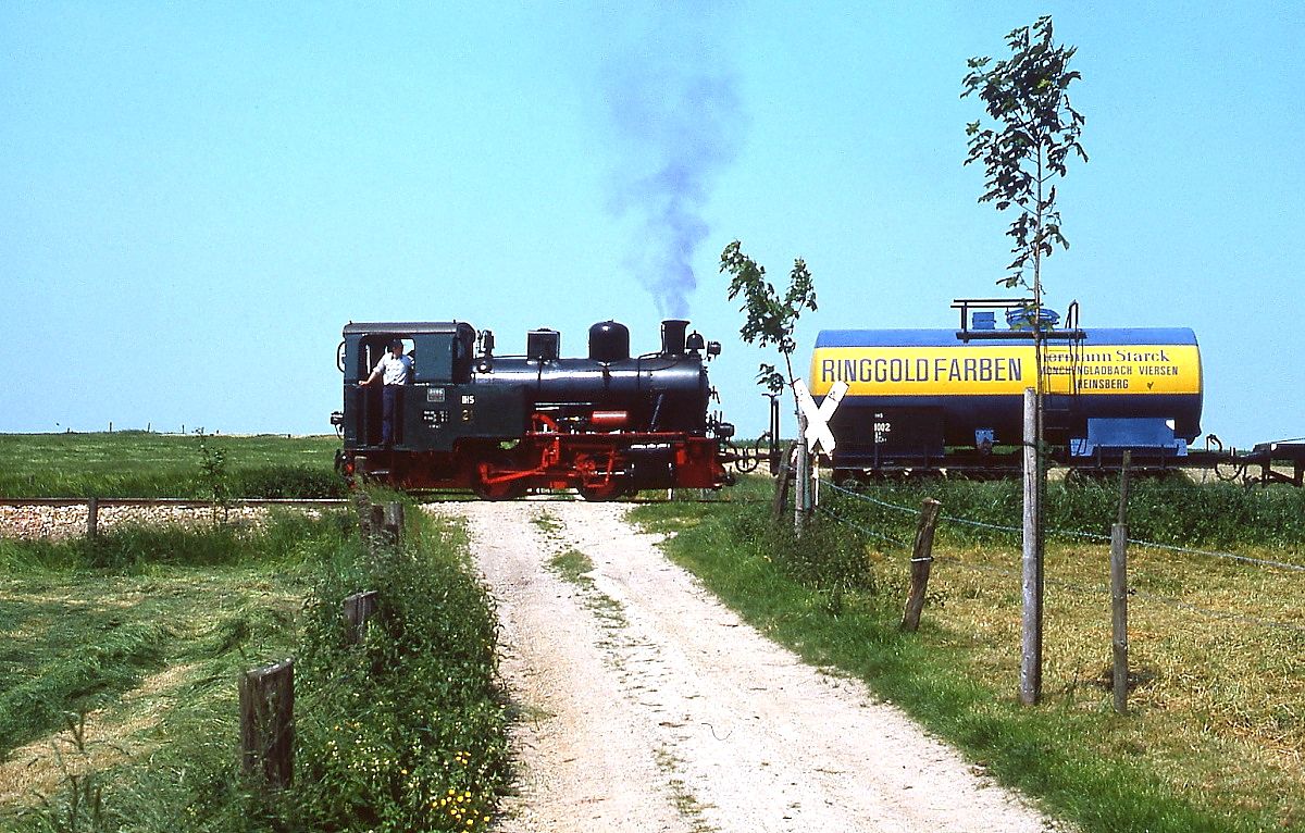 Mitte der 1980er Jahre ist Lok 21 der Selfkantbahn mit einem Fotogüterzug bei Birgden unterwegs. Die Lok wurde 1956 unter der Fabrik-Nr. 12784 von der Lokomotivfabrik Jung in Jungental/Sieg für die Klöcknder-Hütte in Hagen-Haspe gebaut und befindet sich seit 1974 bei der Selfkantbahn.
