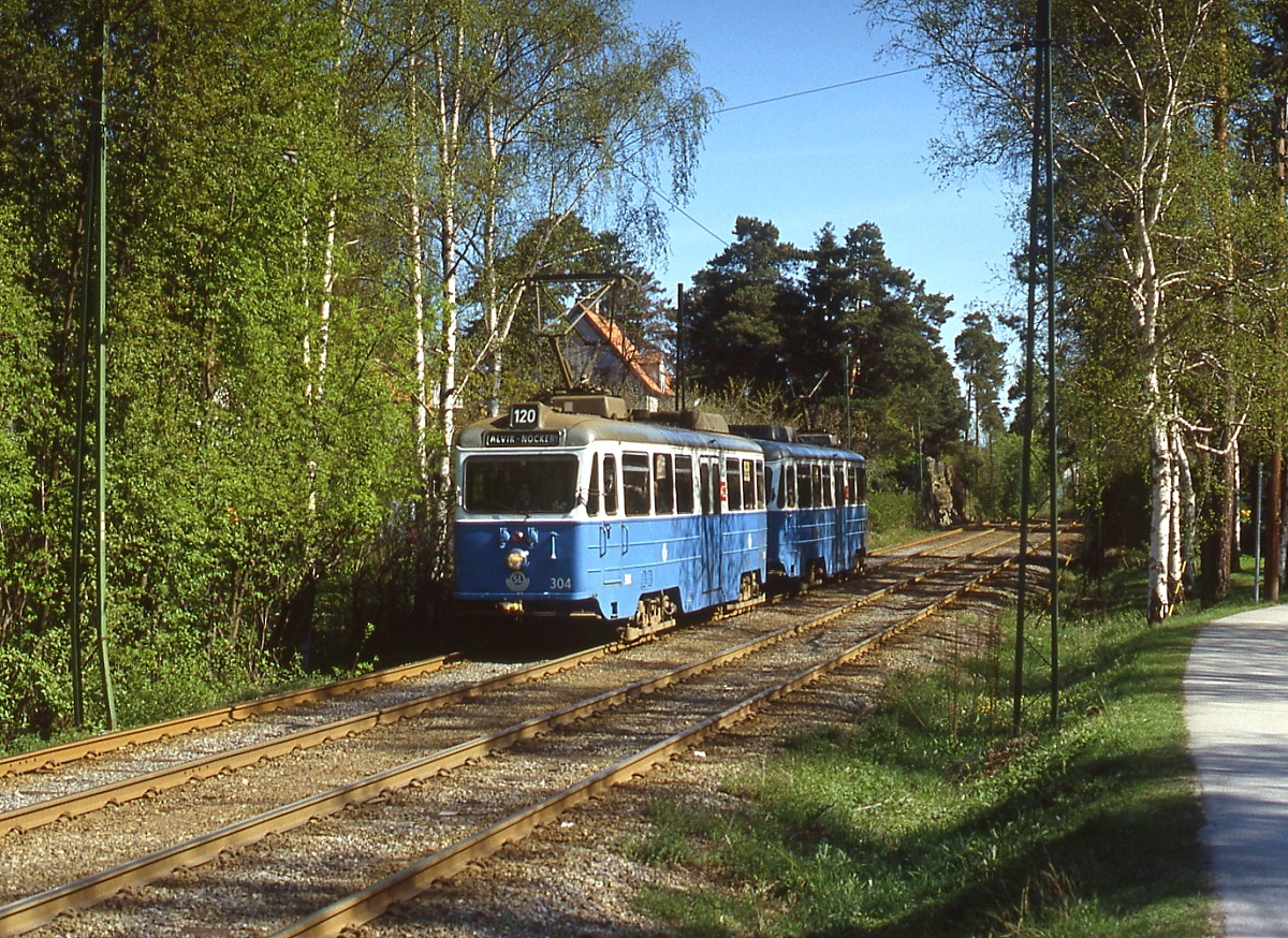 Mitte Mai 1988 sind zwei Triebwagen der Nockebybahn von Alvik nach Nockeby unterwegs, vorne Tw 304. Neben der Lidingöbahn war die Nockebybahn die einzige Stockholmer Straßenbahnlinie, die der Stilllegung im Zusammenhang mit der Umstellung des Straßenverkehrs in Schweden auf Rechtsverkehr 1967 entging. Grund: Nach der Eröffnung der U-Bahn nach Alvik im Jahre 1952 hatte sie keine Verbindung mehr zum übrigen Stockholmer Straßenbahnnetz, außerdem konnten die Mitteleinstiegswagen des ASEA-Typs A 24 problemlos auf Rechtsverkehr umgebaut werden.