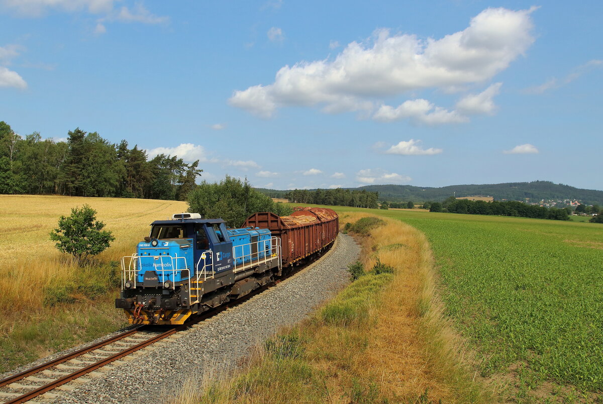 Mn 87301 von As nach Cheb mit der 742 728 und Holz beladenen Waggons. Aufgenommen am 04.07.2023 nahe Vojtanov obec, mit dem Kapellenberg 759m Höhe auf Deutscherseite im Hintergrund.