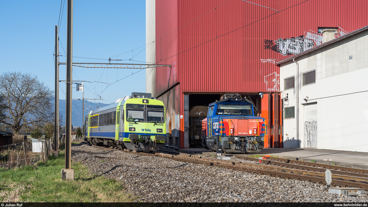 Moderner Getreidetransport bei SBB Cargo am 30. März 2021. Mit der Zweikraftlok Eem 923 026 ab Biel RB in Busswil zwei Tagnpps abgeholt. Der Lokführer erledigt dabei alles alleine, womit ein relativ effizienter Betrieb sichergestellt werden kann.<br>
Hier hat die Lok gerade das Anschlussgleis erreicht. Bereits hat der Lokführer das Tor des Getreidesilos geöffnet um die Wagen abzuholen. Die Entgleisungsvorrichtung ist wieder auf die Schiene geklappt um die Fahrstrasse für den aus Büren an der Aare vorüberfahrenden Regio nach Lyss mit dem RBDe 565 241 zu sichern.