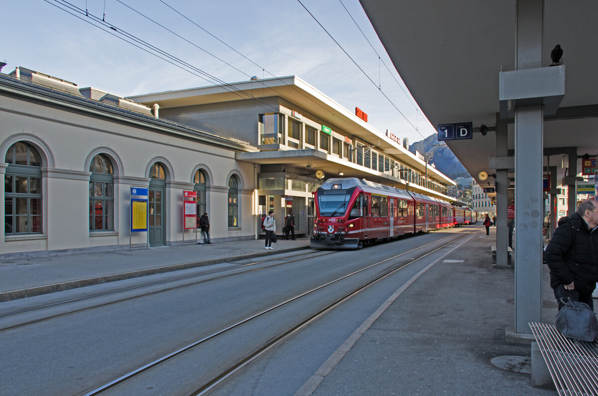 Montag den 05.02.2024 um 10:06 Uhr in Chur (GR). Auf dem Bahnhofvorplatz des Bahnhof Chur steht auf dem RhB Gleis 2 (Spurweite 1'000 mm) der Abfahrbereite Regionalzug R16 mit der Zugnummer 1429 von Chur (ab 10:08 Uhr) nach Arosa (an 11:09 Uhr) bereit. Der Zug hat folgende Formation (Spitze – Schluss von Chur nach Arosa): 1. Fahrzeug: 3512 (Frontanschrift am dreiteiligen Zweispannungs-Triebzuges  Allegra“), Jörg Jenatsch / 3512 (1. Seitenanschrift am 1. Fahrzeug des Zweispannungs Triebzuges  Allegra“), ABe 4/4 35012 (2. Seitenanschrift am 1. Fahrzeug des Zweispannungs-Triebzuges  Allegra“), 2. Fahrzeug: ABe 8/12 3512 (1. Seitenanschrift am 2. Fahrzeug des Zweispannungs-Triebzuges  Allegra“), Bi 35612 (2. Seitenanschrift am 2. Fahrzeug des Zweispannungs-Triebzuges  Allegra“), 3. Fahrzeug: ABe 4/4 35112 (1. Seitenanschrift am 3. Fahrzeug des Zweispannungs Triebzuges  Allegra“), Jörg Jenatsch / 3512 (2. Seitenanschrift am 3. Fahrzeug des Zweispannungs-Triebzuges  Allegra“), 4. Fahrzeug: AB 1564 (Seitenanschrift am Wagen mit öffnungsfähigen Fenstern), 5. Fahrzeug: AB 1562 (Seitenanschrift am Wagen mit öffnungsfähigen Fenstern), 6. Fahrzeug: Bt 52808 (Seitenanschrift am Steuerwagen), 7. Fahrzeug: B 2375 (Seitenanschrift am Wagen mit öffnungsfähigen Fenstern). Koordinaten GMS (Grad, Minuten, Sekunden): N 46° 51’ 10.9’’ O 9° 31’ 44.9’’