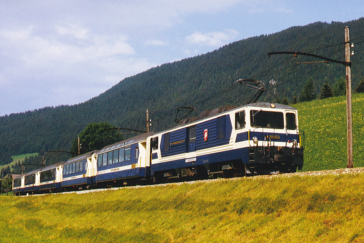 Montreux-Oberland bernois (MOB).
Mit der Inbetriebnahme der neuen Lokomotiven GDe 4/4 6001-6004 im Jahre 1983 sowie der Ge 4/4 8001-8004  im Jahre 1995 hat sich auch die Traktion vom LUXUSZUG verändert.
PANORAMICEXPRESS auf der Fahrt nach Zweisimmen im August 1985 mit GDe 4/4 zwischen Château-d’Oex und Saanen.
Zum Vergleich siehe ID 1262463 und ID 1262521, eingestellt am 3. und 4. August 2021.
Foto: Walter Ruetsch
