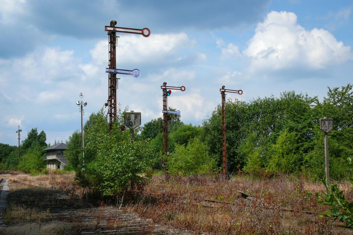 Multikulti im alten Bahnhof Raeren. Auf dem Bild erkennt man alte deutsche Formsignale, sowie zwei belgische SF05-Signale (das S steht für das französische siffler, das F für das niederländische fluiten. In einem zweisprachigen Land - deutsch war damals noch nicht als dritte Landessprache anerkannt - musste man eben an alles denken). Der Lokführer musste also an dieser Stelle das Signalhorn der Lokomotive betätigen, und die Geschwindigkeit auf 5 km/Std herunterfahren. Links im Hintergrund das alte Stellwerkhaus. Das Bild entstand am 05/07/2009 in Richtung Westausfahrt (Eupen).