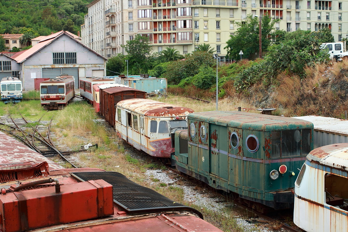 Museum oder Schrottplatz? Zu befürchten ist leider letzteres. Zwischen zwei in den 1960er Jahren für die korsischen Eisenbahnen gebraucht beschafften Billard-Triebwagen der Serie A80D (gebaut zwischen 1938 und 1949) ist die Lokomotive 114 abgestellt (Bastia 15.06.2014). Dabei handelt es sich um einen Eigenbau des Depots Bastia aus dem Jahre 1958. Die Untergestelle stammen vom Billard-Triebwagen 114. Auch die im Hintergrund abgestellten Triebwagen der Reihen X 2000 und X 5000 werden anscheinend nicht mehr benötigt, obwohl sie erst zwischen 1975 und 1981 in Dienst gestellt worden sind.