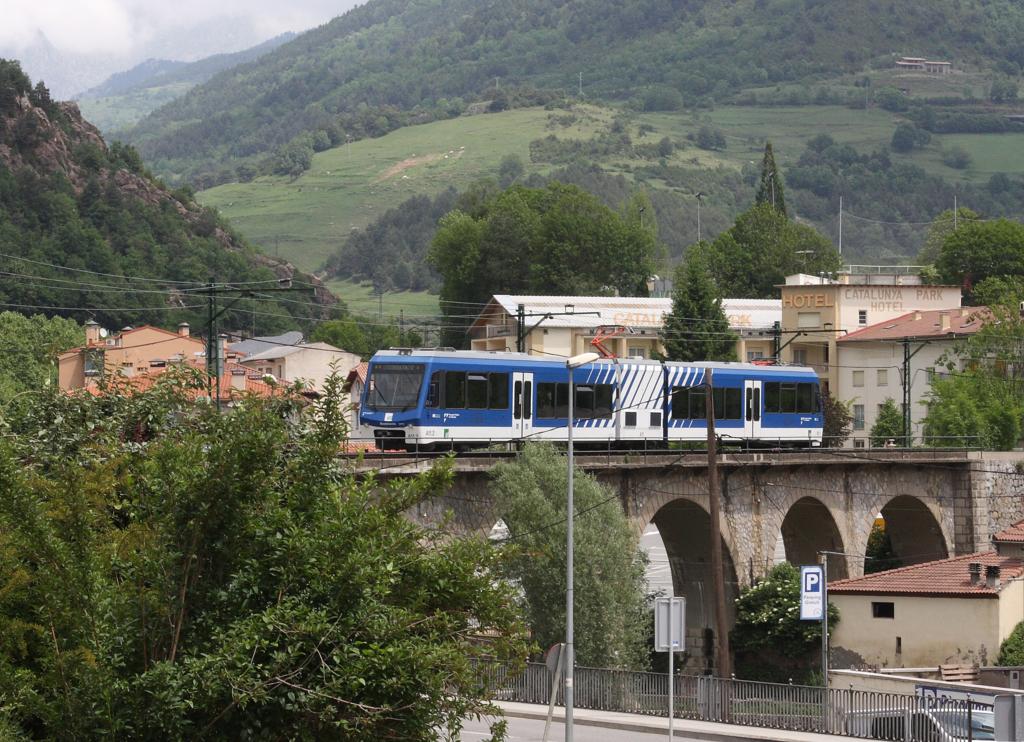 Nach dem Verlassen des Talbahnhofs Ribes Enllac überquert die Zahnradbahn nach Vall de Nuria am Ortseingang von Ribes de Freser mittels eines Viadukts die Nationalstraße. Am 12.6.2015 konnte ich dort den Stadler ET A 11.1 aufnehmen.