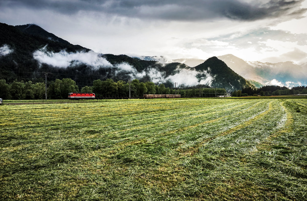 Nach einem Regenschauer lichtet sich die dichte Wolkendecke bei Irschen, während soeben eine 1144 mit einem Güterzug, auf der Fahrt von Lienz nach Villach, vorüber fährt.
Aufgenommen am 16.5.2018.