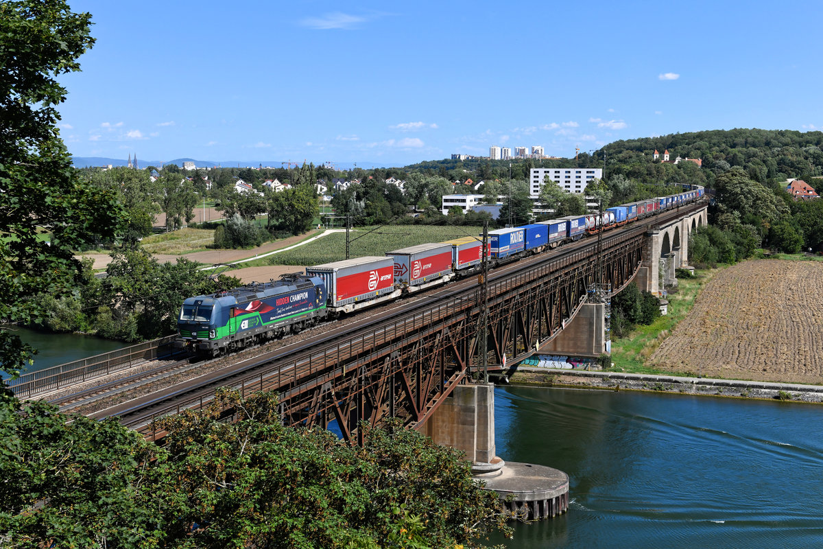 Nach einigen Jahren im Einsatz für LTE fährt die 193 203 des Wiener Leasing-Unternehmens ELL nun für TXLogistik. Mit dem Wechsel des Mieters wurde auch das seitliche Design geändert. Nun weist die Lok auf den Einsatz der Lokomotivführer während der Corona-Pandemie hin, die mit dafür gesorgt haben, dass auch während des Lockdowns Güter zuverlässig ihre Empfänger erreicht haben. Am 26. August 2020 konnte ich den Vectron auf der Mariaorter Eisenbahnbrücke mit dem KLV-Zug DGS 40670 von Curtici nach Köln Eifeltor dokumentieren. 