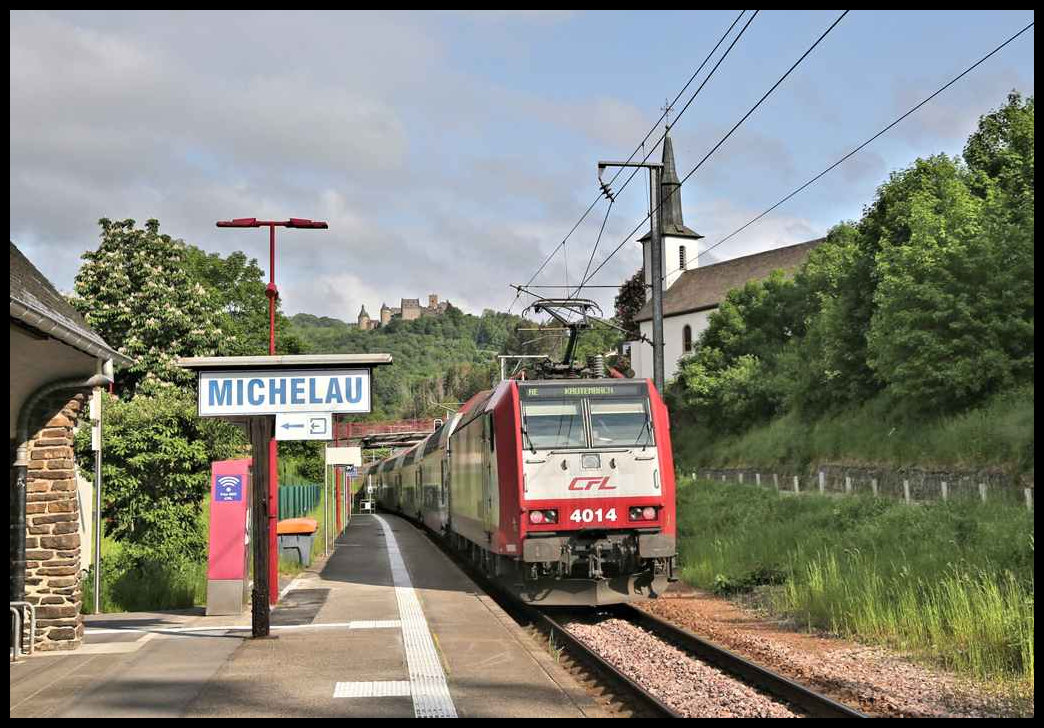Nach kurzem Halt in Michelau am 23.5.2023 um 9.22 Uhr fährt der RE mit CFL Lok 4014 weiter nach Kautenbach. Links neben der kleinen Kirche ist im Hintergrund Burg Bourscheid zu sehen.