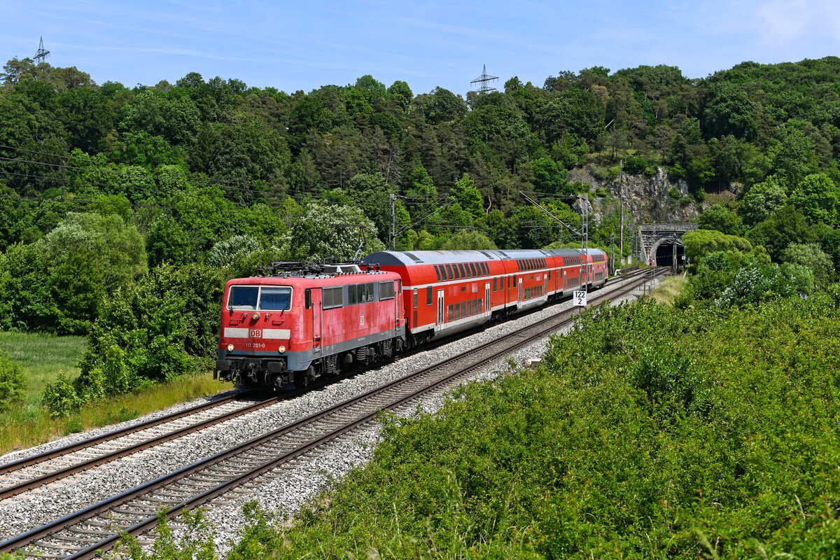 Nach wie vor unverzichtbar sind die Loks der Baureihe 111 bei DB Regio in Bayern. Allerdings ist der Bestand in München und Nürnberg auf inzwischen nur noch knapp über 20 Loks zusammengeschrumpft. Eine davon ist die optisch recht  abgekämpft  wirkende 111 201, aktuell die Lok mit der höchsten Ordnungsnummer der Baureihe (bezogen auf einsatzfähige Loks bei DB Regio). Am 02. Juni 2023 bespannte sie die RB 59154 nach Nürnberg HBF. Der Zug verkehrte anstelle des planmäßigen Triebzug der Baureihe 445. Entstanden ist die Aufnahme bei Esslingen im Altmühltal, kurz nach Verlassen des gleichnamigen Tunnels.