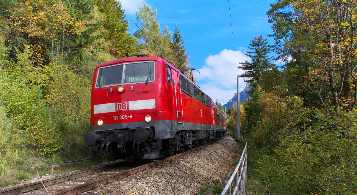 Nachdem die Mittenwaldbahn den Schmalensee umrundet hat, geht es steil bergab ins Isartal. 111 065-9 wird ihre RB aus München gleich zum Zielbahnhof Mittenwald bringen. Strecke 5504 München - Mittenwald Grenze am 07.10.2013