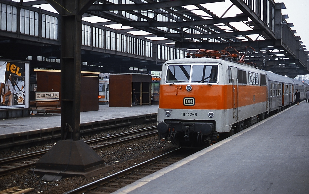 Nachdem der RE 4 am 13.12.2020 auf RRX umgestellt wurde, wird die Baureihe 111 nach über vierzig Dienstjahren m. W. nicht mehr planmäßig im Großraum Düsseldorf eingesetzt. Zeit für eine kleine Reminiszenz: Das Bw Düsseldorf erhielt ab 1979 die fabrikneuen 111 111 - 188 für den Einsatz vor den S-Bahn-Zügen im Rhein-Ruhr-Gebiet, daneben beförderten sie aber auch Nahverkehrs- und Eilzüge. Um 1981/82 steht 111 142-6 vor einem Nahverkehrszug im Düsseldorfer Hauptbahnhof. Sie ist wie die anderen Loks aus dieser Lieferserie in S-Bahn-Farben lackiert, in Dienst gestellt wurde sie am 04.09.1979 und vor etwas mehr als einem Jahr, am 21.02.2019, bei der Fa. Bender in Opladen zerlegt. Zum Zeitpunkt der Aufnahme wurde der Düsseldorfer Hauptbahnhof umgebaut, mit dem Abriss der alten Hallendächer war bereits begonnen worden.
