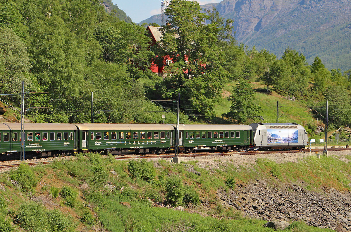 Nachdem unser Zug in Richtung Myrdal weitergefahren ist, kann man sehr gut den noch in Berekvam stehenden Zug 1855 in Richtung Flam sehen, die Zuglok ist El 18 2255, die Schlusslok ist noch außerhalb des Sichtbereichs. Die Trassierung dieser Strecke mit einem Gefälle von 55 Promille über weite Strecken und Gleisbögen mit kleinsten Radien  von 130 m ist schon ein Meisterwerk, vor allem da ein Großteil der 20 Tunnel manuell, also ohne große maschinelle Hilfe, aus dem Gestein herausgebrochen wurde. Am 31.05.2018 geniessen wir nur das tolle Wetter.  