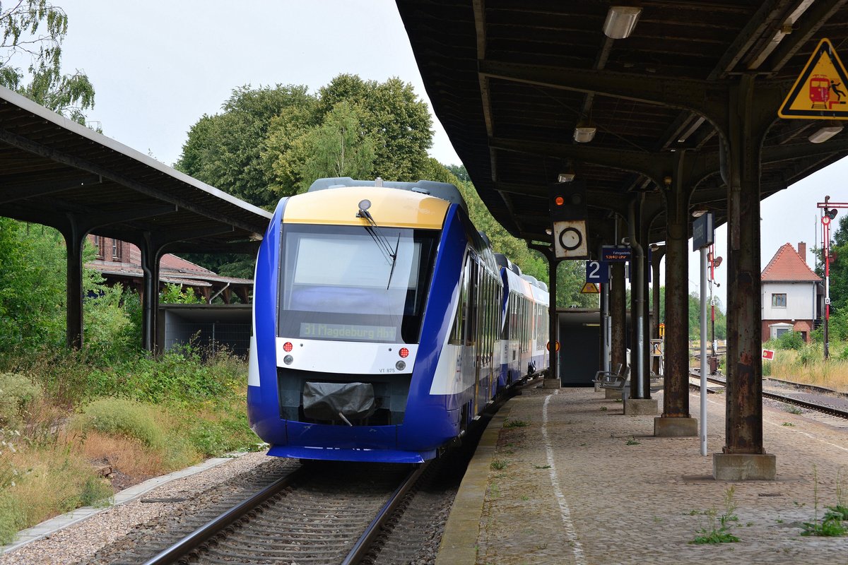 Nachschuss auf den VT875 als HEX31 nach Blankenburg. Der Zug wird in Halberstadt geteilt. Nach dem Befehl darf der Zug an dem Halt zeigenden Hauptsignal vorbei fahren. Grund dafür ist eine Bahnübergangsstörung wo der Bahnübergang nicht mehr geschlossen hat. Schon bald alles Geschichte. Der Harz-Elbe-Express wird zum Fahrplanwechsel vom Schienennetz verschwinden, denn Abellio hat die Ausschreibungen beider Lose für das Dieselnetz Sachsen-Anhalt für sich entscheiden können. Nicht nur der HEX wird hier Vergangenheit sein denn ab kommenden Fahrplanwechsel wird der Halt in Blumenberg aufgeben. Zur Zeit wird nur noch bei Bedarf gehalten. Ab 2020 wird die Strecke auf 120km/h durchgängig umgebaut und Blumenberg auf ESTW umgebaut. Somit werden auch die mechanischen Stellwerke und Formsignale verschwinden sondern wohl auch die Bahnsteige in Blumenberg. Von der einsitigen Bedeutung als Knotenpunkt dürfte nach dem Umbau nichts mehr zu sehen sein. In Blumenberg trafen sich die Strecken Blumenberg-Wanzleben-Eilsleben, Blumenberg-Schönebeck, sowie Blumenberg-Egeln-Staßfurt welche zwischen 1999 und 2002 alle samt stillgelegt wurden und somit nur noch die Verbindung Magdeburg-Halle blieb. 

Blumenberg 21.07.2018