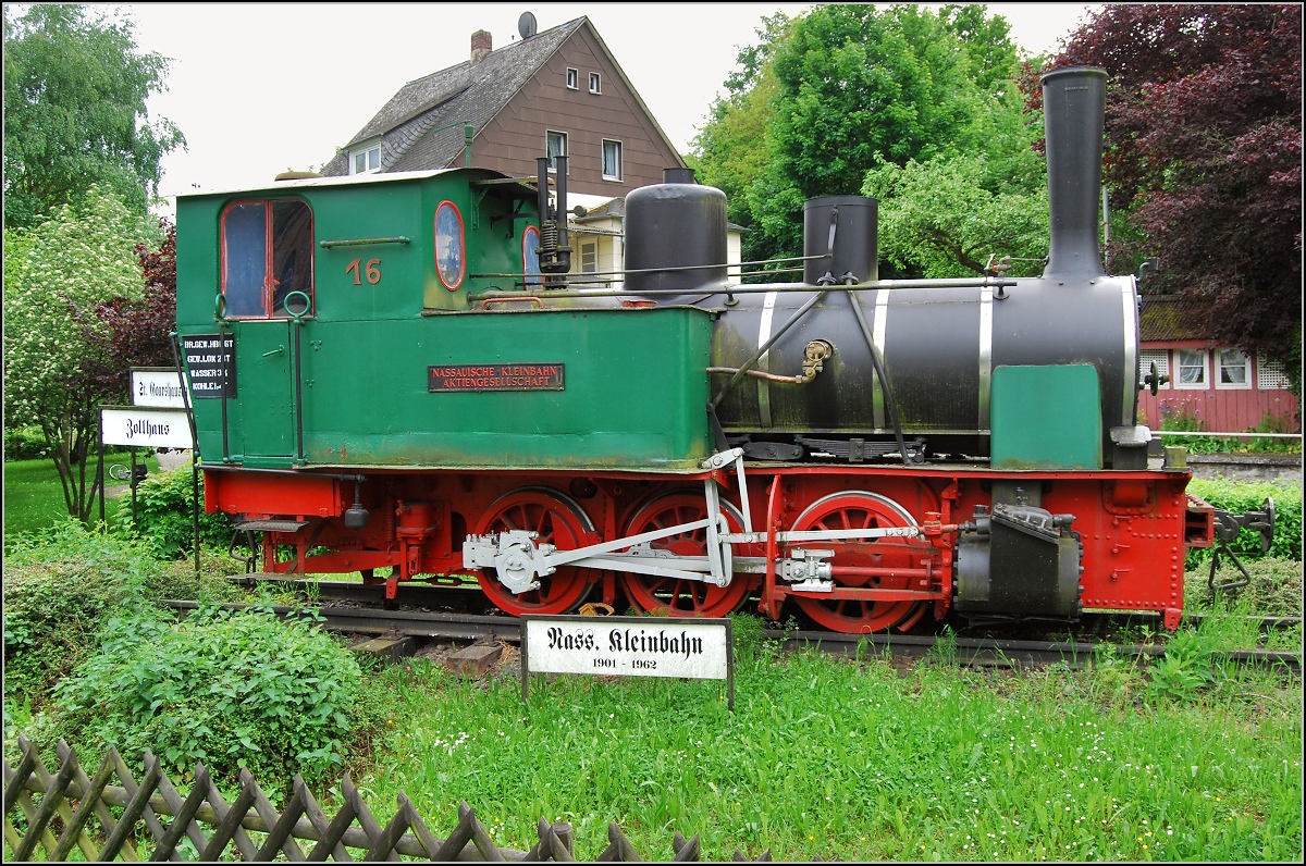 Nassdampflok Nr. 16 der Nassauischen Kleinbahn in Nast�tten. Hier soll sich die Strecke nach St. Goarshausen und Zollhaus verzweigt haben, wie hinten mit Schildern angedeutet ist. nach rechts ging es wohl in den Bahnhof und weiter nach Braubach. Ich war sehr �berrascht, mitten im Nirgendwo auf dieses Relikt zu stossen. Ein rein dokumentarisches Foto, da ich noch kein Bild hierzu fand. Die Lok wurde 1900 gebaut und war bis 1957 origin�r bei der Kleinbahn Selters-Hachenburg eingesetzt. Anschlie�end 5 Jahre am Endpunkt der Strecke in Zollhaus in Betrieb. Sie war baugleich zur Orignalausstattung dieser Strecke, Loks 1-8, 25 t, 30 km/h und 160 PS. In Zollhaus gab es Anschluss an die ebenfalls mittlerweile historische Strecke, Wiesbaden–Diez (Lahn).