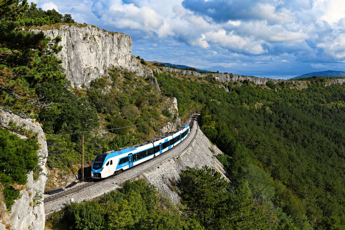 Natürlich machte ich mich auch zu einem Spaziergang zum allseits bekannten Aussichtspunkt bei Črni Kal auf. Dort konnte ich eine der wenigen Reisezugleistungen auf der Koper-Rampe fotografieren. Inzwischen hat das Fahrzeugmaterial der SŽ eine deutliche Modernisierung erfahren. Der nagelneue, von Stadler Rail gebaute 510 018 fuhr am 18. September 2021 als S2 502 von Koper nach Hodos und hatte zum Aufnahmezeitpunkt erst wenige Minuten seiner über fünf Stunden dauernden Reise quer durch die kleine Alpenrepublik bis zur ungarischen Grenze absolviert.  