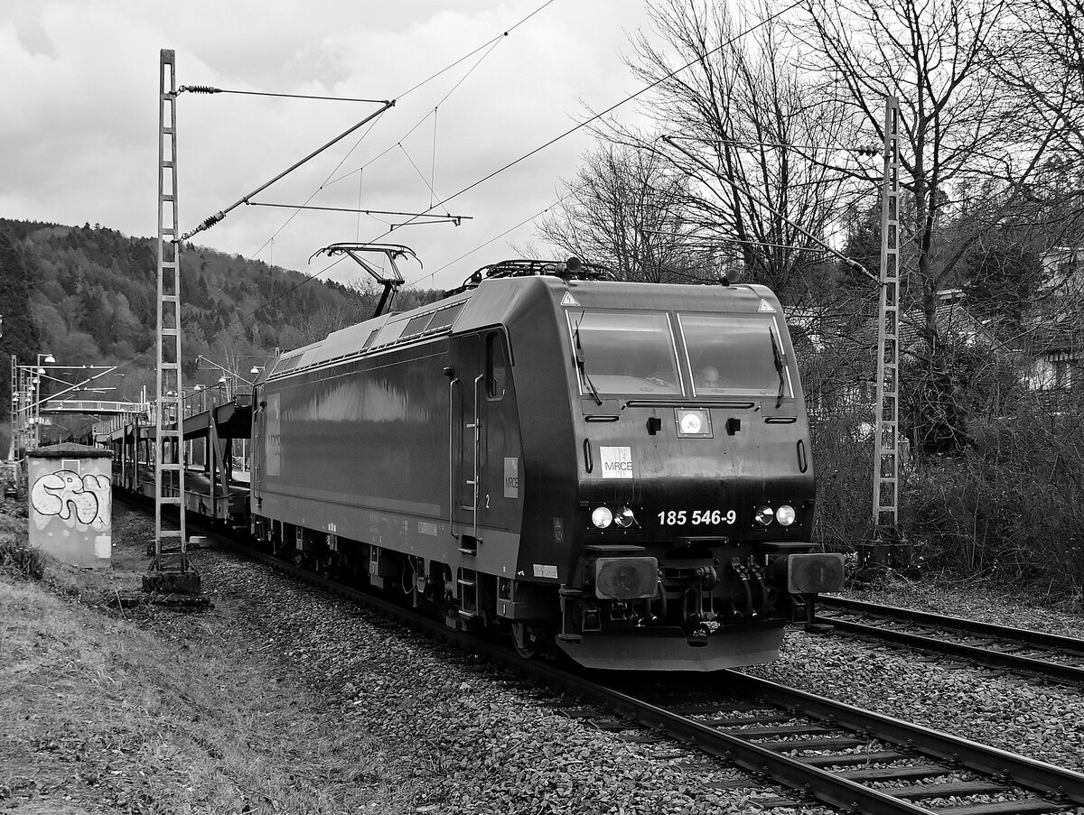 Ne Schwarze in schwarz/weiß, alias 185 546-9 von MRCE mit leeren Autotransportwagen am Haken in Neckargerach am 15.2.2022 gen Bad Friedrichshall Hbf fahrend.