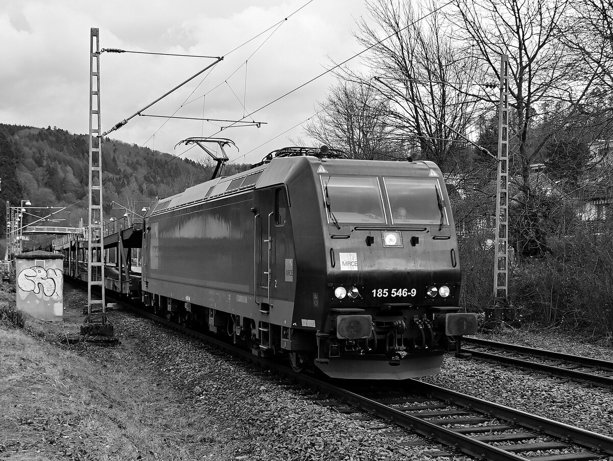 Ne Schwarze in schwarz/weiß, alias 185 546-9 von MRCE mit leeren Autotransportwagen am Haken in Neckargerach am 15.2.2022 gen Bad Friedrichshall Hbf fahrend.