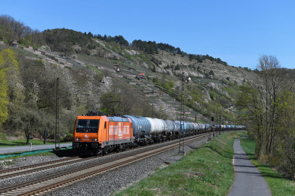 Neben DB Cargo trennte sich inzwischen auch die SBB Cargo von einigen ihrer Traxx-Maschinen. 482 048 wurde bereits 2019 an die Hamburger Rail Service GmbH & Co. KG veräußert. Beim neuen Eigentümer erhielt die Lok eine orangene Folierung. Interessanterweise ist sie aber noch bei den SBB Cargo immatrikuliert, wie ein Blick auf die Loknummer am Seitenrahmen verrät. Am 16. April 2022 konnte ich die auf den Namen Joel getaufte Lok mit einem Kesselwagenzug bei Gambach im frühlingshaften Maintal fotografieren.