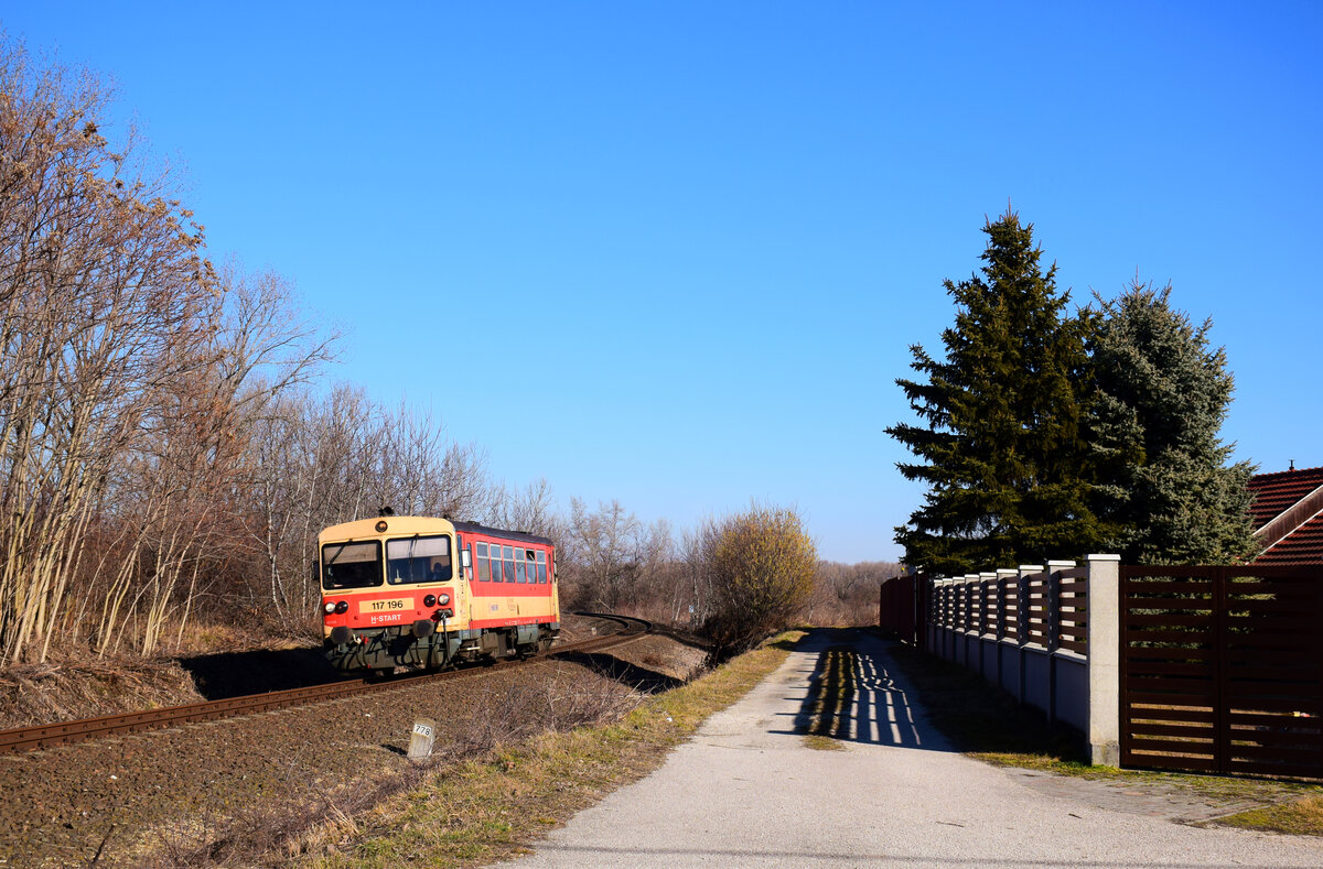 Nebenbahn-Idyll auf der KBS 5. Die 117 196 (Bzmot 196) als Regionalzug 32922 von Esztergom nach Székesfehérvár über Komárom kurz vor der Haltestelle Szőny-Déli.
13.02.2022.