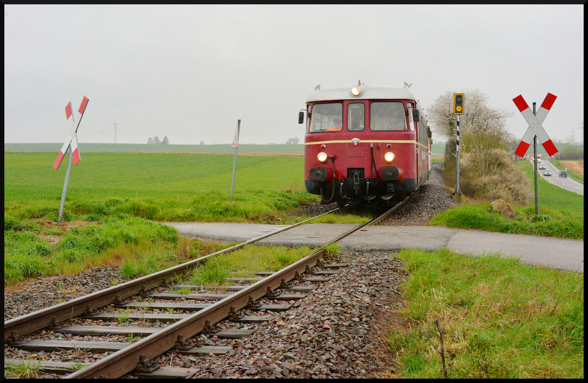 Nebenbahn-Romantik:  Der Rebenbummler  (Eisenbahnfreunde Breisgau, EFB VT 27 mit VT 28) kommt am regnerischen 16.04.2023 auf der Krebsbachtalbahn von Hüffenhardt nach Neckarbischofsheim Nord kurz vor Siegelsbach an einem unbeschrankten Bahnübergang vorbei.