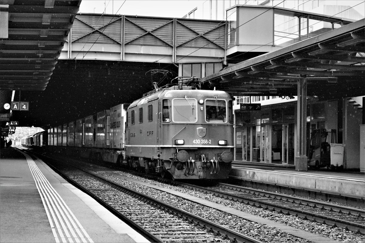 Nein, kein Schneefall, sondern nur Regenfall: SBB Re 430 258-2 durchfährt unter schlechten Lichtverhältnissen mit einem gemischten Inlandsgüterzug, darunter einige Migros-Kühlkontainern, den Hauptbahnhof Winterthur, in Richtung Effretikon. Freitag, 5. Januar 2018