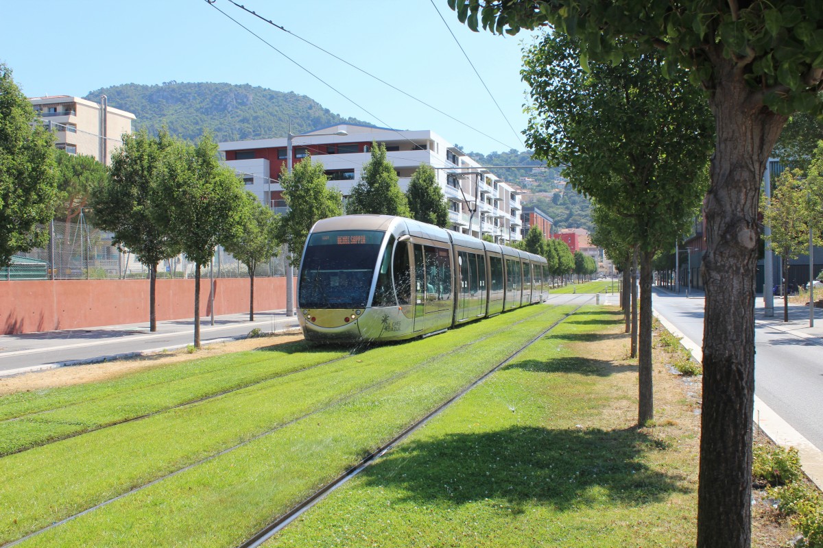 Nice / Nizza Lignes d'Azur SL T1 (Alstom Citadis-402 14) Boulevard Francois Mitterand am 25. Juli 2015. - Als die Strassenbahn gefahren kam, war die Berieselungsanlage der grasbewachsenen Gleisanlage tätig.