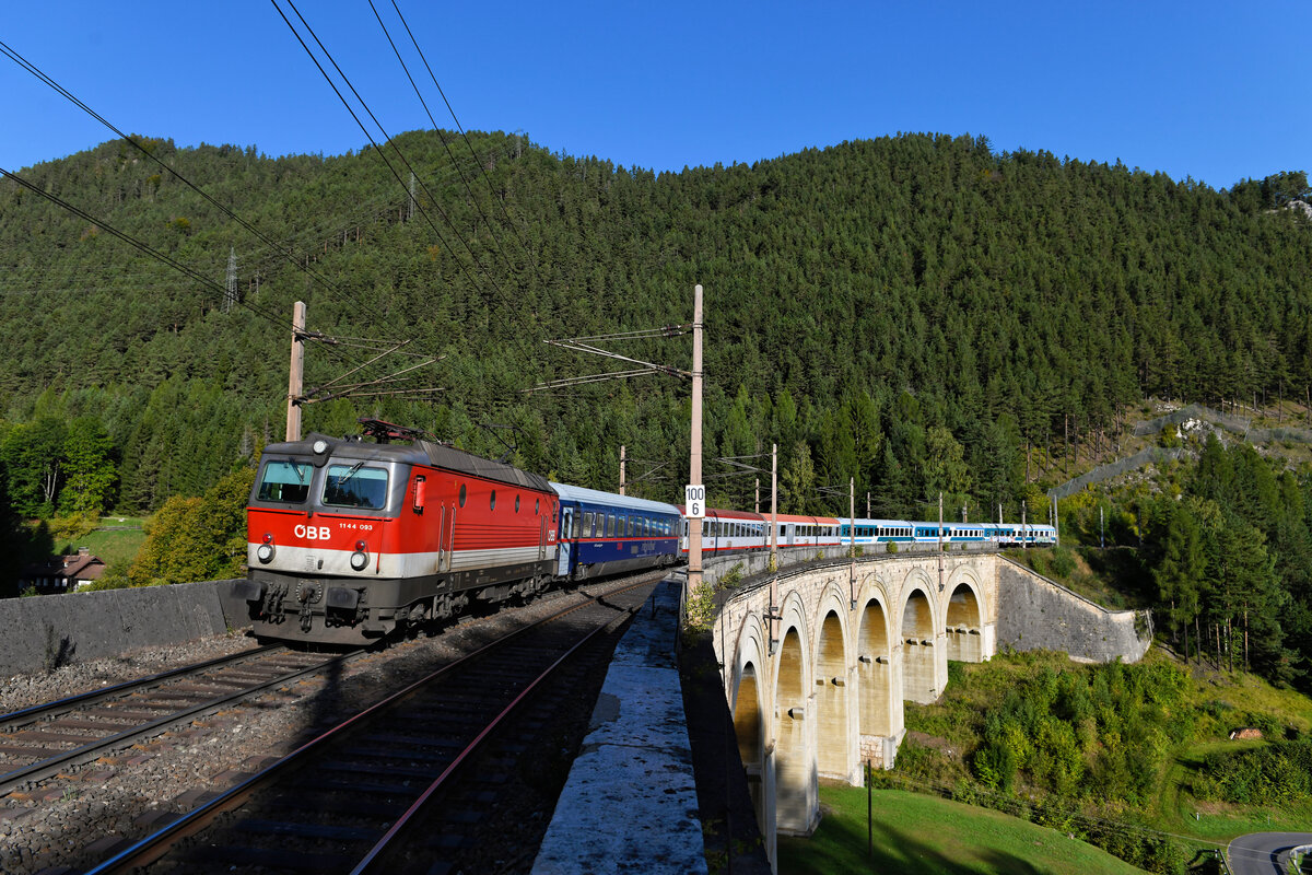 Nicht ganz so spektakulär wie das Krauselklause-Viadukt ist das Bauwerk, welches den unteren Adlitzgraben überspannt. Hier ist man genau 100 Kilometer von Wien entfernt, Luftlinie ist es um einiges weniger, muss die Bahn doch aus dem Wiener Becken kommend, erst etliche Höhenmeter in geschwungener Streckenführung gewinnen. Am 26. September 2021 konnte ich auf der zum Aufnahmezeitpunkt fast 170 Jahre alten Brücke die 1144.093 vor ihrem EC 151  Emona  nach Ljubljana aufnehmen. 