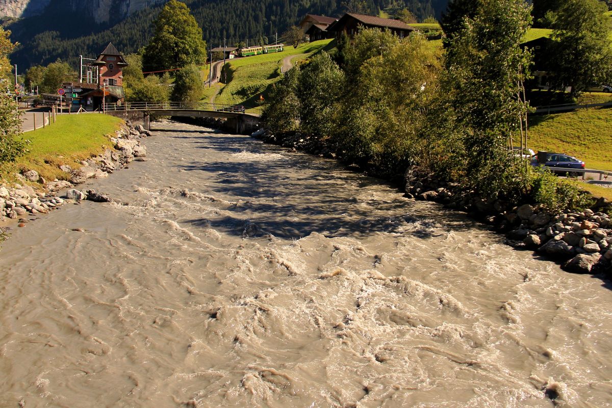 Nicht zu Unrecht heisst das Grindelwaldner Tal auch Tal der Schwarzen Lütschine. Im Hintergrund fährt WAB-Triebwagen 111 mit Steuerwagen 226 als Leerzug auf die Kleine Scheidegg. 7.September 2016. 