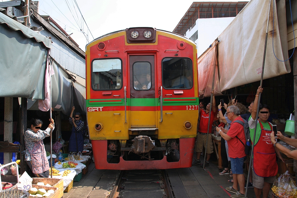 NKF 1227 (1A' 2', dh, Fuji Heavy Industries, Bauj.1985) als letztes Fahrzeug des ORD 4384 nach Ban Laem fährt am 20.November 2019 durch den bei der Mae Klong Station gelegenen Markt.