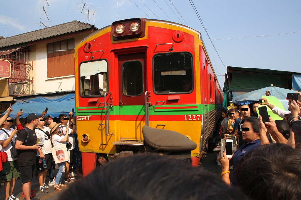NKF 1227 (1A' 2', dh, Fuji Heavy Industries, Bauj.1985) als erstes Fahrzeug des ORD 4385 von Ban Laem erkämpft sich am 20.November 2019 bei der Mae Klong Station seinen Weg durch die, mit Bussen angescharten, Touristen.