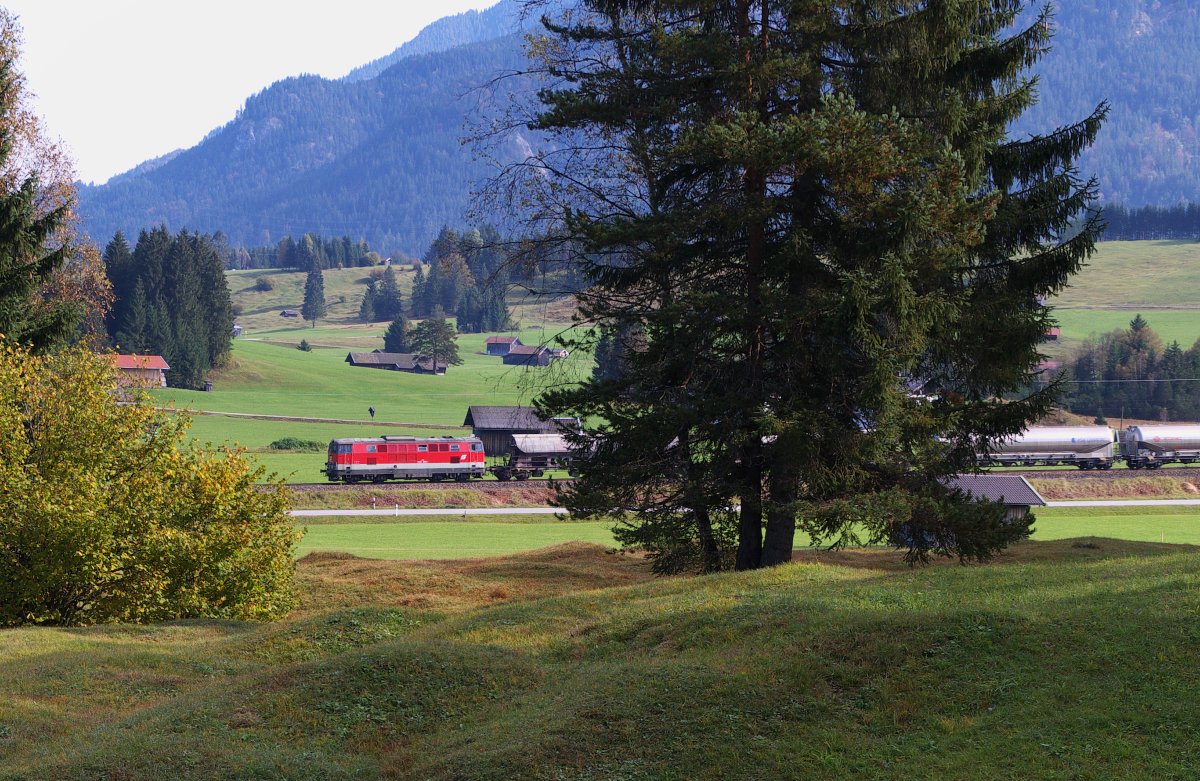Noch einmal zurück gerannt....Wir waren schon auf Wanderschaft zum Wildensee und hatten unser Feriendomizil verlassen, da pfiff es im Wäldchen hinter Klais. Die RB nach Mittenwald war schon vorbei, eigentlich war Zugpause angesagt. Gerade an diesem Tag rollte der Güterzug Vils (Tirol) - Garmisch-Partenkirchen - Innsbruck - Hall (Tirol) zwei Stunden früher als sonst über die Gleise und noch in einer besonderen Bespannung. Also wir 100 Meter zurück gesprintet und schon rauschten zwei Tauri am Landhaus Wackerl vorbei. Im Normalfall sind ein Hercules und ein Taurus am Zug und es kam noch etwas nach........UND das war eine 2143er als Schubunterstützung! 
Bahnstrecke 5504 München Hbf. - Mittenwald Grenze - 06.10.2014