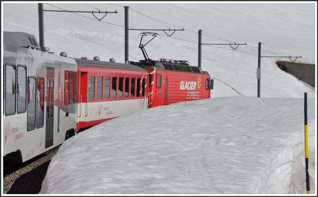 Noch liegt viel Schnee auf dem Oberalppass. Der R852 mit der HGe 4/4 4  Täschhorn  beginnt die Talfahrt nach Disentis kurz hinter der Passhöhe. (22.04.2015)