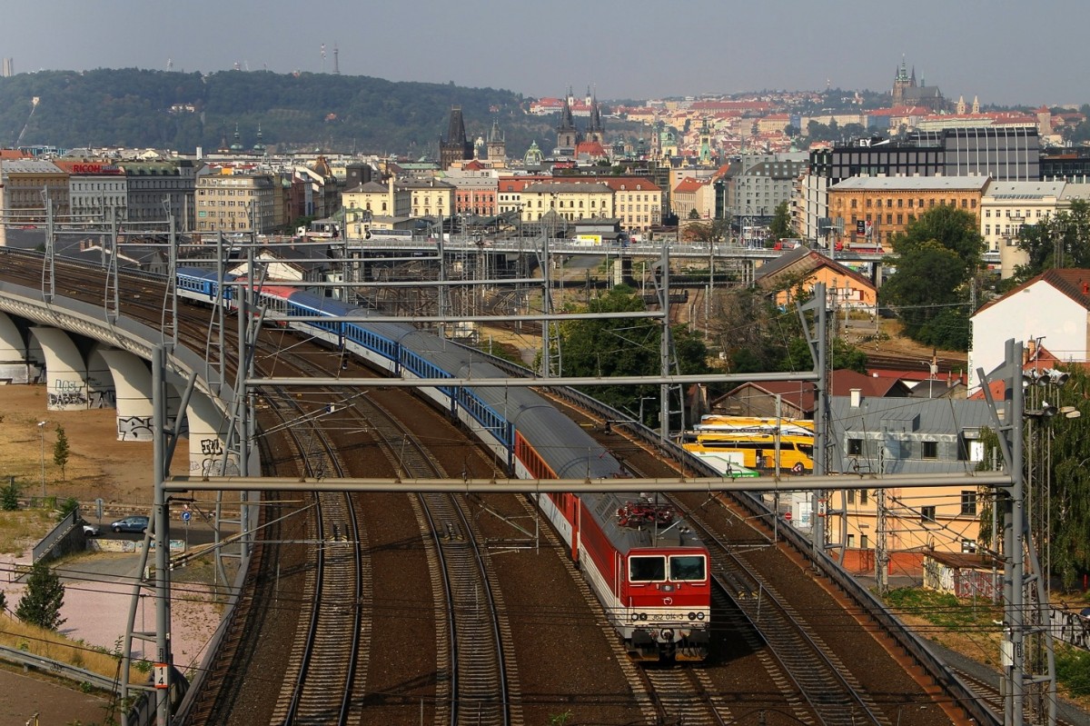 Nochmasl die 362 014-3 welche nun mit einigen Wagen den Prager Hbf verlässt. Bild gemacht am 12.08.2015. Im Hintergrund der kleine Bahnhof Praha Masarykovo nádraží für die Regionalzüge und die Stadt Prag mit der Burg.