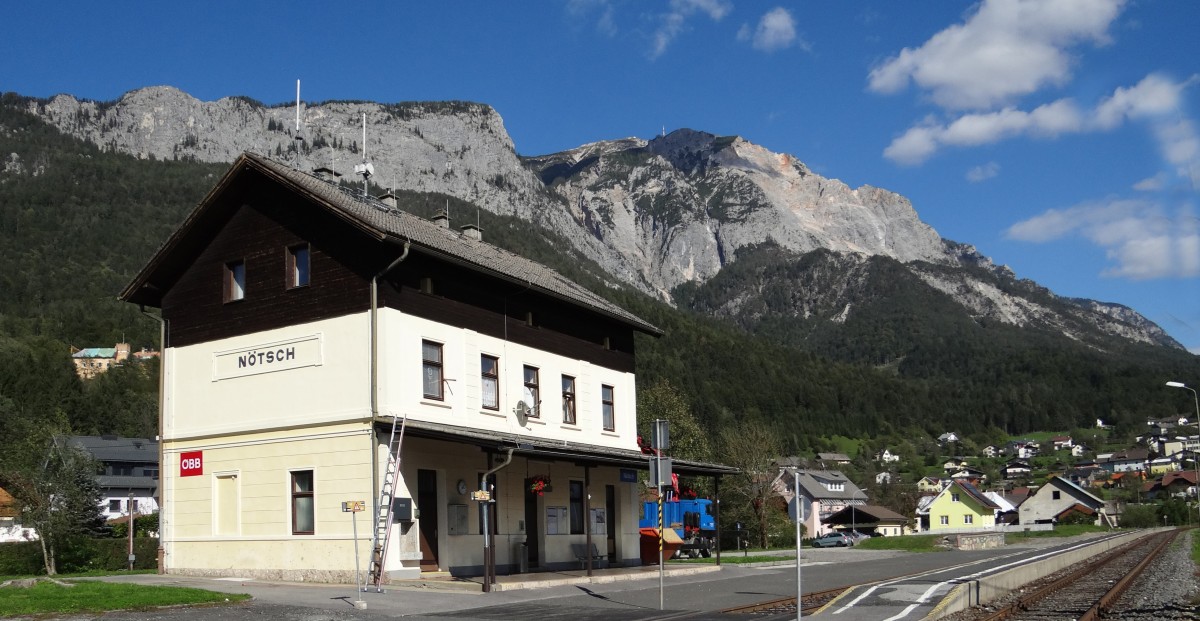 Nötsch, der erste Bahnhof der Gailtalbahn im km 8.850, 559 m ü.A., im Hintergrund das mächtige Massiv des Dobratsch 2.166 m. Nötsch gehörte ursprünglich zusammen mit Hermagor und Kötschach-Mauthen zu den mit Fahrdienstleitern besetzten Bahnhöfen, dazwischen versahen Geschäftsführer den Dienst. Ab 1993 wurde die Strecke mittels Zugleitbetrieb vom Bahnhof Hermagor aus gesteuert.[2015-09-29]