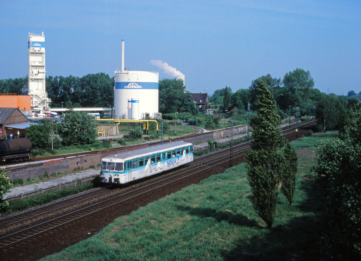  Nokia-Bahn  wurde die heutige Glückaufbahn von Gelsenkirchen über Wanne nach Bochum für ein paar Jahre genannt - so lange, wie eben der finnische Mobilfunkkonzern in Bochum sein Werk betrieben hat. Einher gehend mit einer PR-Kampagne für die am Haltepunkt Bochum Nokia (vormals und heute wieder: Riemke), wurden sogar einige Wanner Akku-Triebwagen mit Werbung und in entsprechendem Outfit der 1990er Jahre gestaltet. So auch 515 554, der am 15. Mai 1994 soeben die alten Industrieanlagen von Herne-Holsterhausen als CB 6023 passiert. Alles - wie so vieles im Revier, Geschichte.