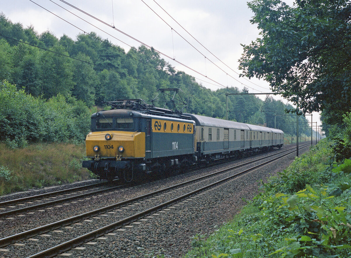 NS 1104 mit Zug 32108 (Emmerich - Utrecht GE) bei Ede am 24.08.1991, 10.25u. Expressgüterzug aus 3 x Dms905 der DB, aufgenommen von einem Forstweg aus. Scanbild 95706, Kodak Ektacolor Gold.