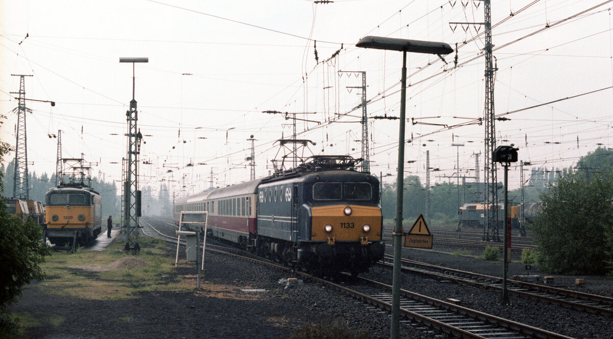 NS 1133 mit TEE-11  Rembrandt  (Amsterdam CS - Stuttgart Hbf) bei Ankunft in Emmerich am 04.06.1982. Links steht NS 1309 und rechts wartet NS 1207 mit Güterzug. Scanbild 92742, Kodacolor400.