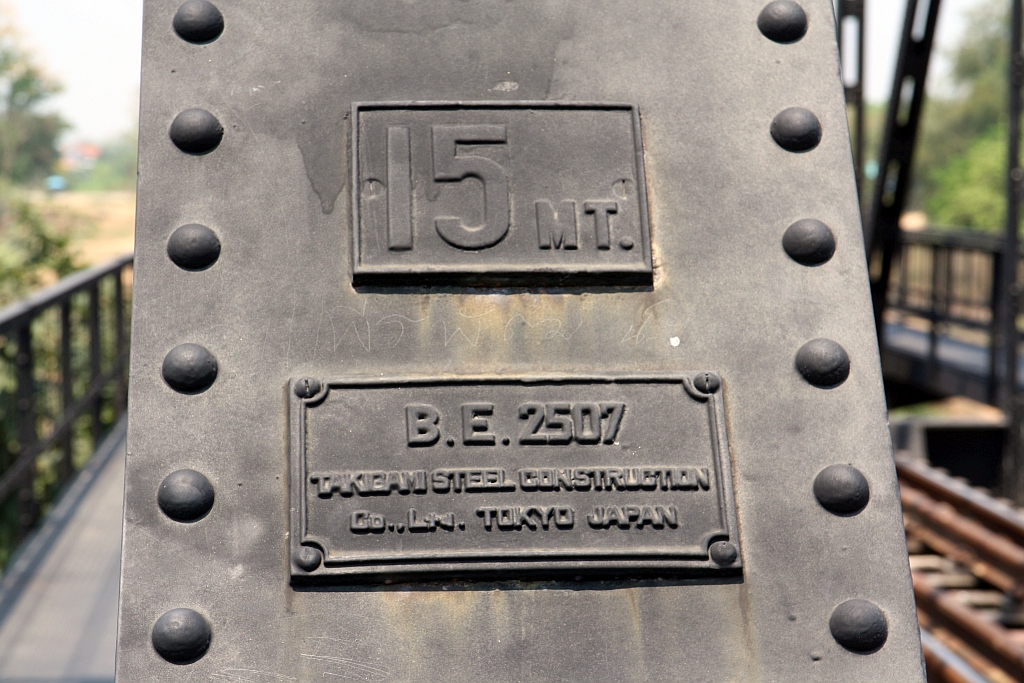 Nur 1 Kilometer von der Nakhon Lampang Station in Richtung Norden entfernt befindet sich eine 296,68m lange Stahlbrücke über den Mae Nam (=Fluss) Wang. Von den 9 Brückenfeldern sind 5 als trapezförmige Fachwerkbrücke ausgeführt. - Nach den Standards der SRT mit 6 Farbschichten (3 x Braun, gefolgt von Weiß, Grau und die äußersten Schicht Schwarz) gegen Korrosion geschützt ist die letzte Farbschicht der Ursprung des Spitznamens  Saphan Dam  (=Schwarze Brücke). - Am 20. Dezember 1916 eröffnet, wurde die Brücke am 3.Jänner 1944 von Flugzeugen bombardiert und minimal beschädigt. Noch heute sind Spuren von Granatsplittern und Schussspuren erkennbar. - Von 1964 bis 1966 erfolgte durch die japanische Takigami Steel Construction Co., Ltd. die Sanierung der Kriegsschäden. Auf diese Sanierung weist das Bild vom 24.März 2023 hin.