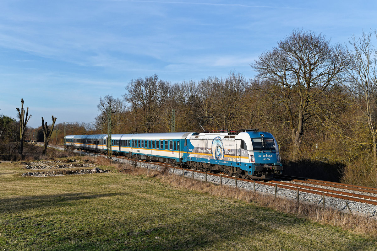 Nur auf einer Seite trägt die 183 004 die Werbung für das Prag-Ticket. Am 16. März 2020 bespannte sie den ALX 79856 von Hof nach München HBF und konnte im sanften Abendlicht an der Stadtgrenze bei Oberschleissheim fotografiert werden. 