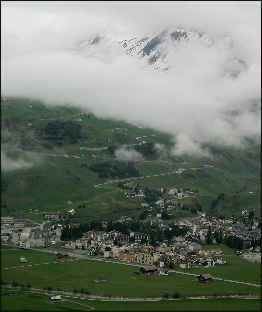 Nur ein Hauch von Zug -

Andermatt mit dem dahinter liegenden Hang von Nordwesten aus gesehen. 
Den Bahnhof von Andermatt erkennt man am linken Rand vom Ort. 

Die Strecke nach Hospental folgt am unteren Ortsrand der Umfahrungsstraße. Die Strecke nach Göschenen führt vom Bahnhof nach links aus dem Bild. 
Die Strecke nach Nätschen führt vom Bahnhof aus nach oben um nach einem Rechtsbogen zur ersten Kehre fast am rechten Bildrand, etwas weiter oben links sieht man dann das Tunnelportal nach der Kehre. Die Strecke führt im schräg ansteigend nach links bis zum Tunnelportal der nächsten Kehre. Dort ist auch ein Regionalzug gerade so erkennbar. Nach dieser Kehre kann man die Strecke wieder in die andere Richtung verfolgen, bis sie hinter den Wolken verschwindet.

22.05.2008 (M)
