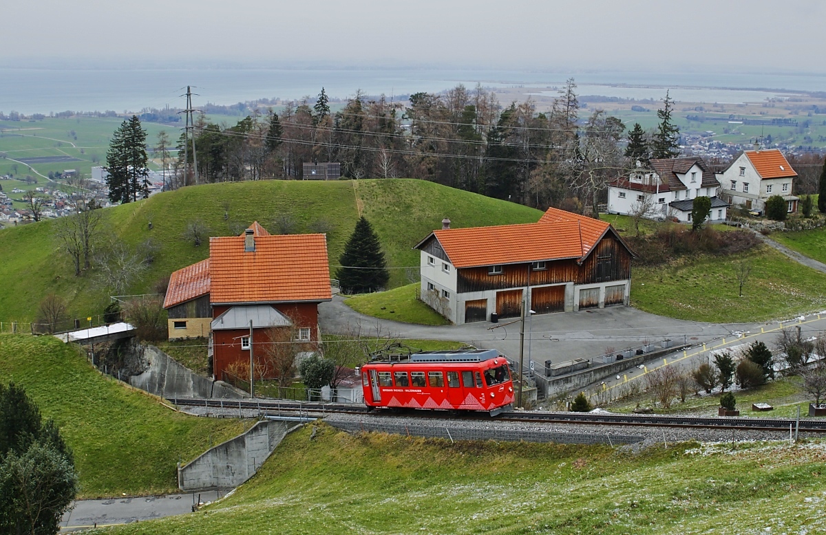 Nur noch wenige Meter und die S 26 alias BDeh 1/2 1 der Bergbahn Rheineck-Walzenhausen hat am 27.02.2023 die Endstation Walzenhausen erreicht, im Hintergrund der Bodensee und das Rheindelta
